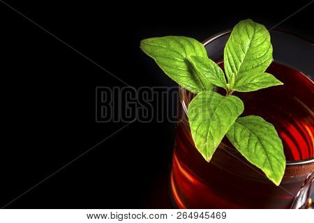 A Mug Of Tea On A Black Background, And Next Is A Green Mito