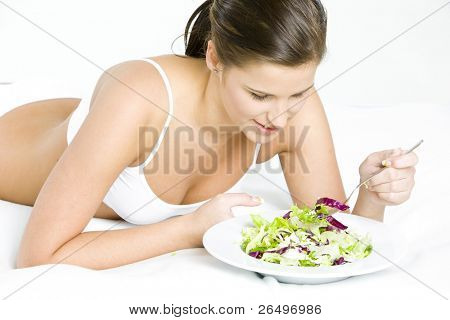 liggende kvinde spiser salat