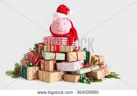 Piggy Bank In Santa Claus Hat. Christmas Gift Boxes. White Background. The Concept Of Saving.