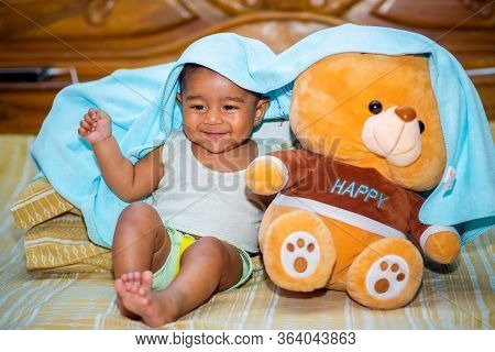 A Six Months Age Asian Baby Boy Playing A Yellow Taddy Bear.