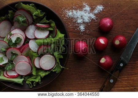 Fresh Radish, Lettuce And Parsley Salad In A Brown Ceramic Bowl On A Wooden Cutboard