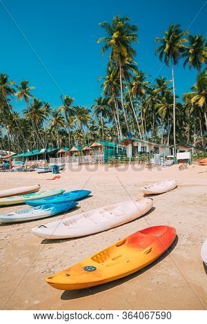 Canacona, Goa, India. Canoe Kayak For Rent Parked On Famous Palolem Beach On Background Tall Palm Tr