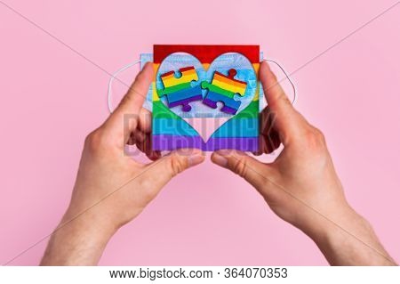 Lgbt Symbol Frame Heart In Male Hands Inside Puzzles Painted By A Rainbow On A Medical Mask. Coronav