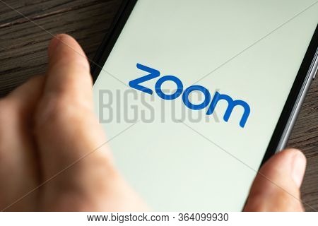 Phone With A Hand Showing Zoom Cloud Meetings App. Work And Have Meetings From Home With A Smart Pho