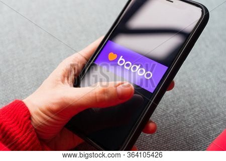 Young woman holding a smartphone with a Badoo dating app on screen. IPhone 11 with a social media ch