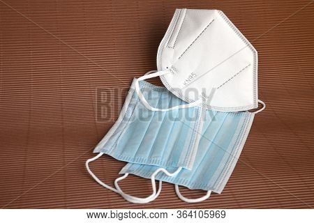 detail of a group of ffp2 and surgical protective masks on a brown background. Covid19 or Coronaviru