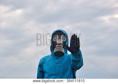 Horizontal Outside Picture Of Liquidating Man Raising One Hand, Wearing Gas Mask, Gloves And Protect