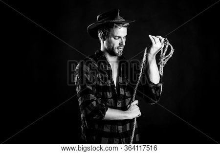 Western Life. Man Unshaven Cowboy Black Background. Man Wearing Hat Hold Rope. Lasso Tool Of America