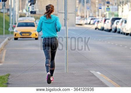 Slim Girl Running On The Sidewalk Along The City Street, Rear View. Alone Runner, Concept Of Workout