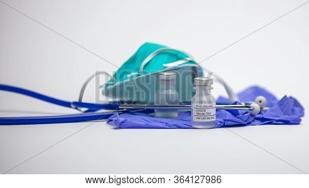 Covid-19 Vaccine Test Vials On Top Of Medical Rubber Gloves With A Stethoscope And Respirator Mask I
