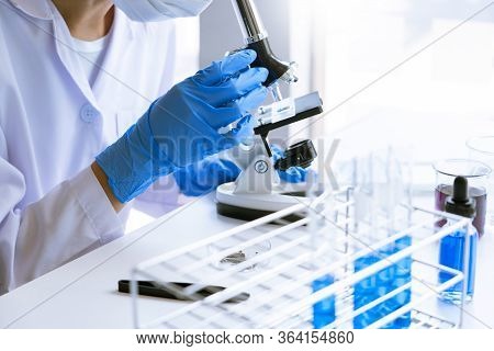 Young Asian Scientist Working Looking Through A  Microscope Doing Research For Analyzing A Experimen
