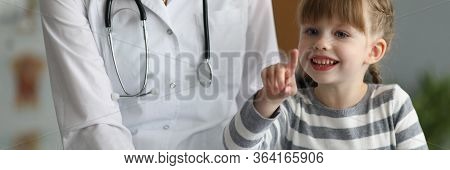 Close-up Of Smiling Child Pointing Finger And Holding Paper Folder. Happy Kid Looking At Camera With