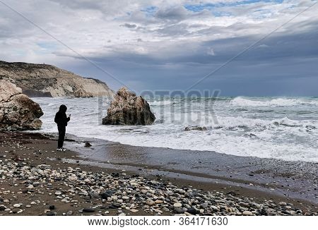Unrecognized Person Enjoying The Stormy Seascape With Windy Waves. Rock Of Aphrodite Birthplace, Pet