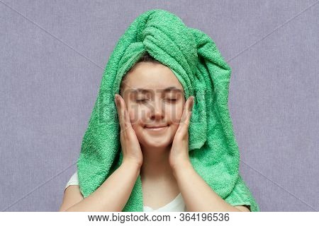 Happy Young Girl With Clean Skin And With A Green Towel On Her Head Puts Hands To Face