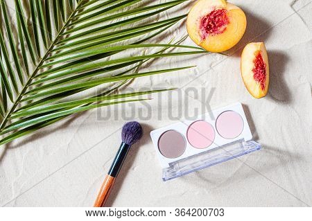 Vacation. A Sculpting Palette And A Blush Brush Lie On The Beach Sand, Surrounded By Vibrant Fruits,