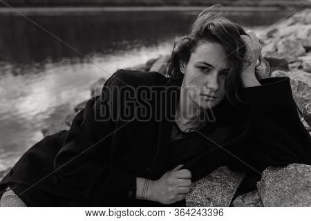 Woman In The Coat Lying On The Stones Near The River