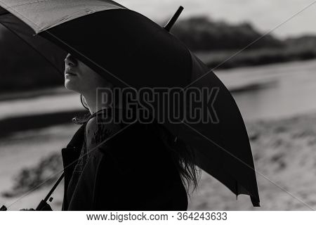 Woman In The Coat Looking Out Of The Umbrella
