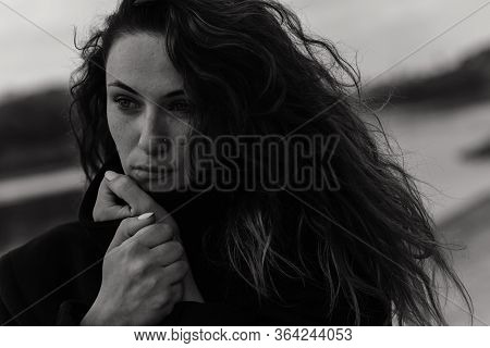 Woman In The Coat Looking To The Side And Holding Her Hands Near The Chin