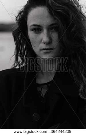 Serious Curly Woman With Dark Hair In The Coat