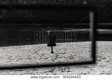 Woman In The Coat Standing On The River Bank Photographed From The Back