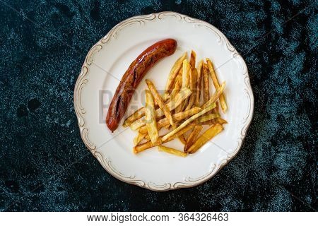 Homemade Sausage With Skinny French Fries Potatoes In Plate Also Called Peruvian Salchipapa.