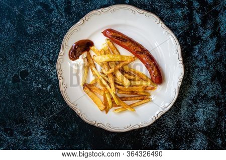 Homemade Sausage With Skinny French Fries Potatoes In Plate Also Called Peruvian Salchipapa.