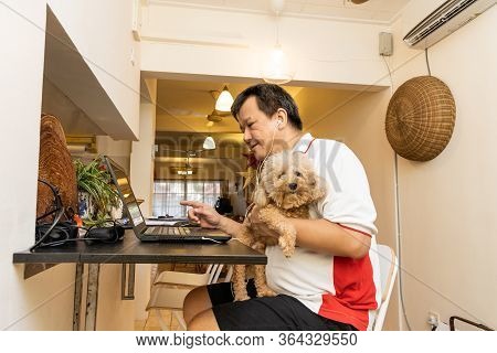Matured Asian Business Man Work From Home Accompanied By Pet Dog During Lockdown In Malaysia