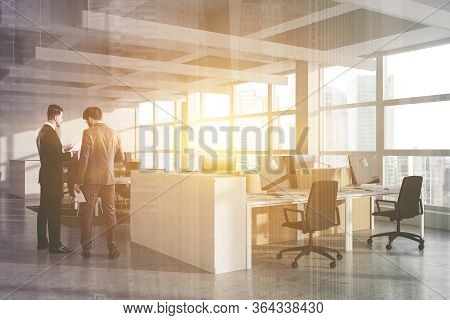 Two Businessmen Talking In Modern Open Space Office With White Walls, Cubicles With Computer Tables 