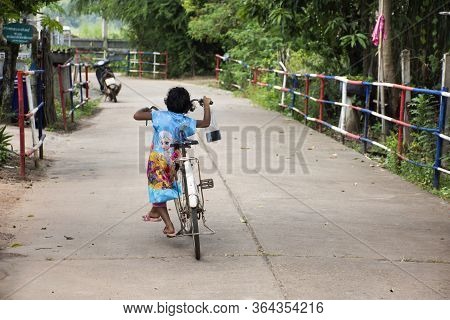Bueng Kan, Thailand - October 3 : Thai Little Girl Biking Bicycle On Street Of Small Village At Rura
