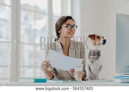 Photo Of Happy Businesswoman Works From Home On Self Isolation, Holds Papers, Checks Information On 