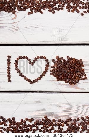 Roasted Coffee Beans In A Shape Of Letter I And Heart. Heap Of Coffee Beans On White Wood. I Love Co