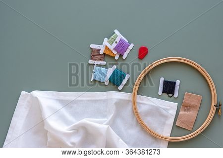 Embroidery Tools On Green Background With Wooden Embroidery Hoop, Needles, Needle Threader And Color