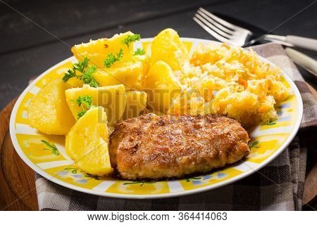 Minced Pork Cutlet Served With Potatoes And Sauerkraut Salad.