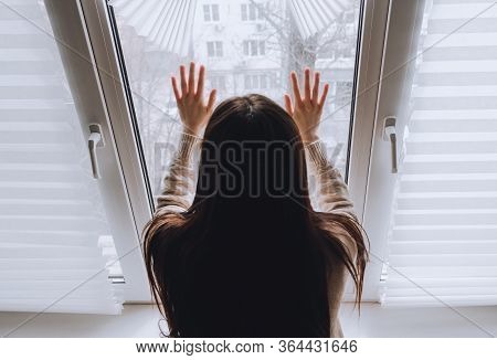Female Touches Hands To The Window Glass, Concept Of Quarantine Or House Arrest