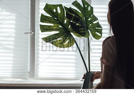 Creating Comfort At Home. Woman With A Vase And Artificial Leaves For Decoration. Home Improvement, 