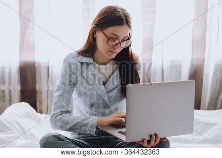 Remote Work At Home, Female On The Bed During The Day Working With A Laptop, Looking On The Screen.