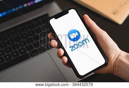 A Hand Holding A Cell Phone. App Logo On The Smartphone Screen.
