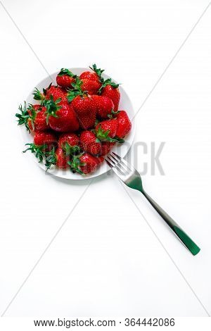 White Plate With Strawberries On A White Background, And A Fork. Beautiful Still Life. Tasty Fruits.