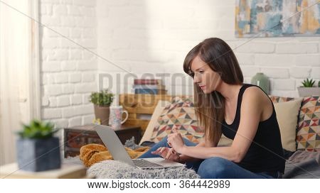 Stay at home and work in home office - Casual woman sitting on bed working online from home with laptop computer.