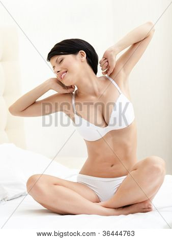 Halfnaked kvinde strækker sig på sengen, hvid baggrund