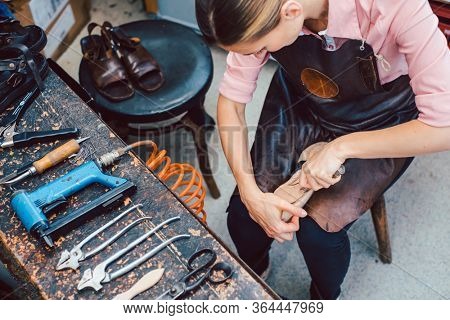Shoemaker working on the frame of a shoe with lots of tools on the workbench
