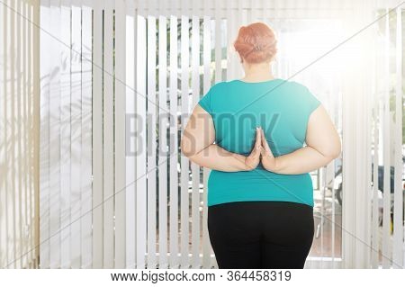 Standing Plus Size Woman Doing Reverse Prayer Pose To Strengthen Her Arms, View From The Back