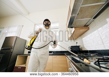 Technician In Protective Suit And Mask Spraying Chemicals In House To Prevent Spreding Pneumonia Vir