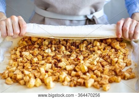 Hands Wrap The Dough With Apple Filling Make Apple Strudel.girl Is Preparing A Pie At Home In An Apr