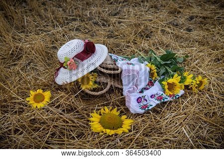 Still Life Of Hats And Baskets With Sunflowers On A Mowed Field