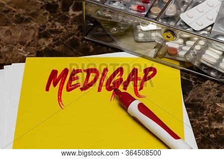 Medigap Is Written In Red Letters On A Yellow Sheet Lying On The Table Next To A Box Of Pills. Medic