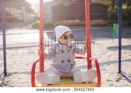 Adorable Little Girl On The Swing Set In Playground. Happy Little Girl Have Fun. One And Hulf Year G
