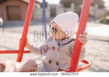 Adorable Little Girl On The Swing Set In Playground. Happy Little Girl Have Fun. One And Hulf Year G