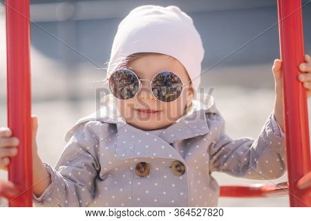 Adorable Little Girl On The Swing Set In Playground. Happy Little Girl Have Fun. One And Hulf Year G