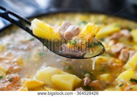 Background Stewed Potatoes With Meat On A Plastic Black Spoon Close Up